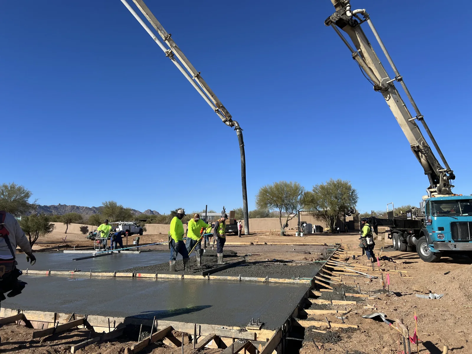 Concrete pump truck placing a slab while the crew screeds it in Gilbert, AZ